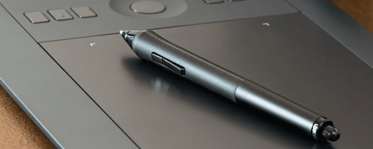 Close-up image of a black writing pen laying on top of a laptop mouse pad.
